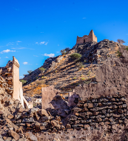 Historic fort and stone ruins built on a rocky hill surrounded by desert landscape.