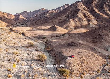 Aerial view of a 4x4 vehicle and tent at a remote camping spot in Wadi Qor, UAE.